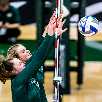 two players blocking volleyball at the net